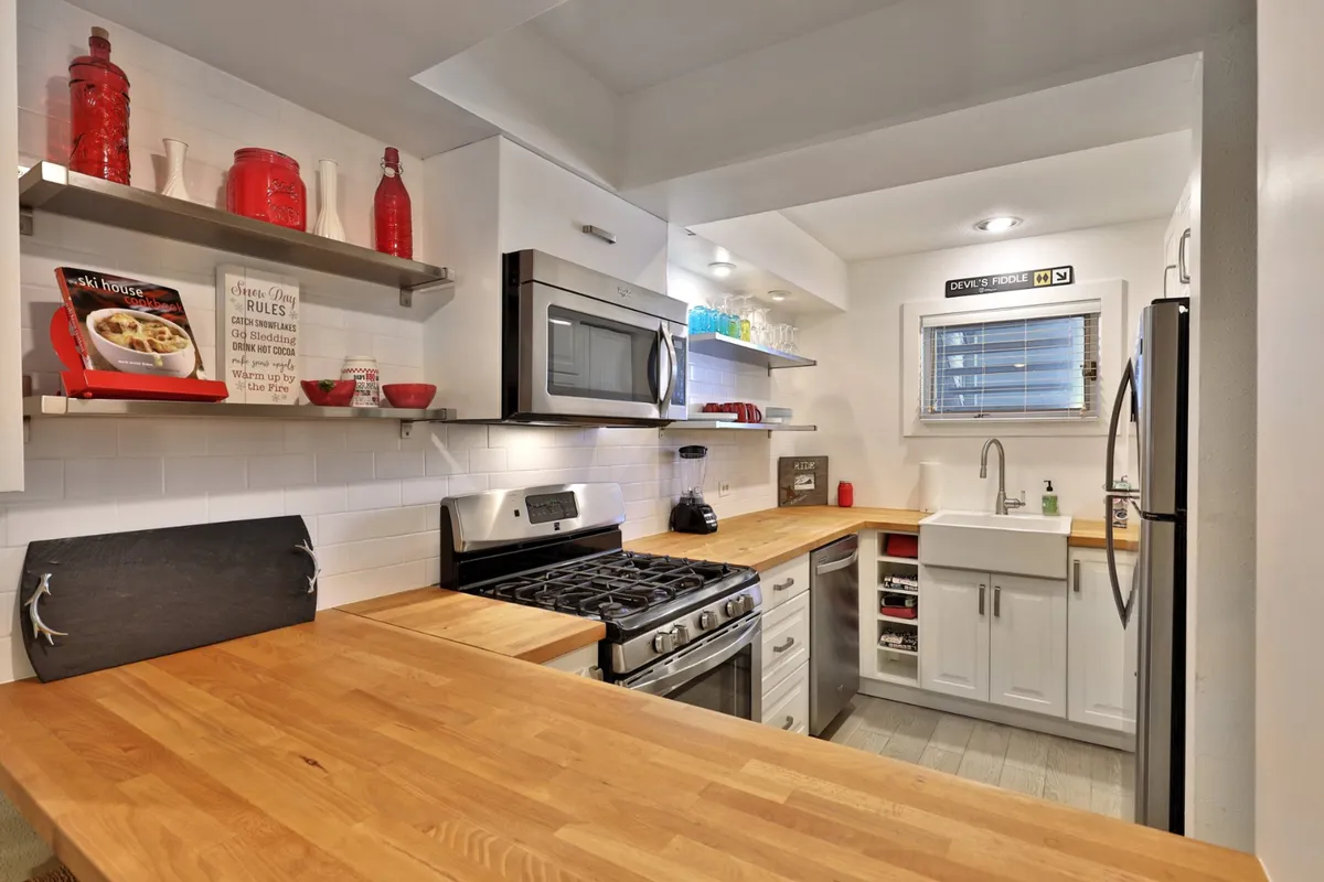 A well-equipped kitchen with wooden countertops, stainless steel appliances, and open shelving. The layout encourages social cooking and entertaining, making it ideal for preparing home-cooked feasts after a day in the mountains.